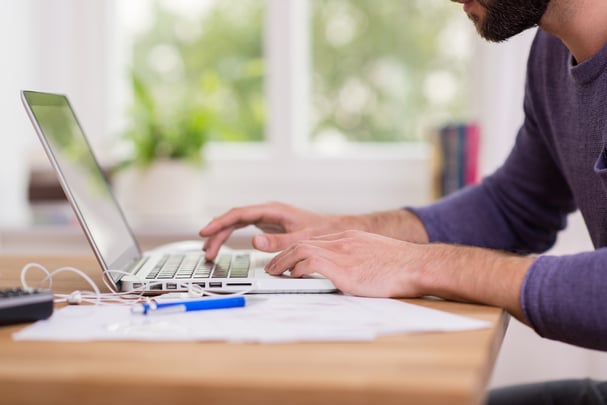 A man sitting at a desk using a laptop computer